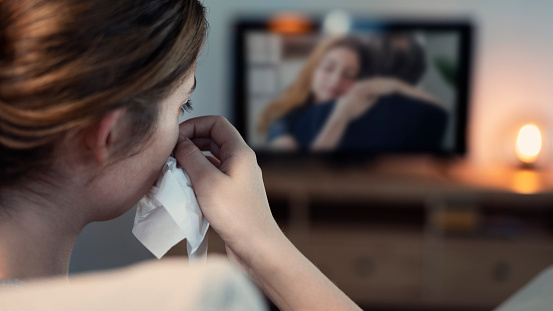 woman crying while watching tv in the night